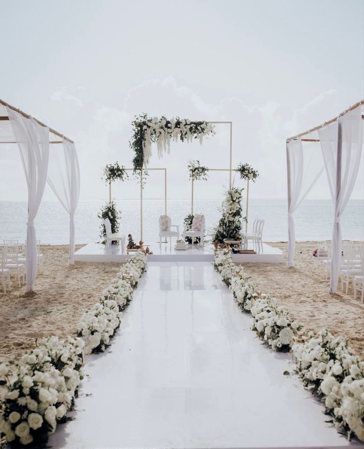 A white-and-gold beach ceremony aisle